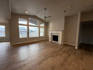 Unfurnished living room with a fireplace, hardwood / wood-style floors, vaulted ceiling, and ceiling fan