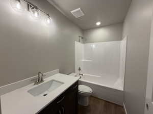 Full bathroom featuring hardwood / wood-style floors, vanity, toilet, and shower / bath combination