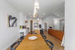 Dining room with light hardwood / wood-style floors, lofted ceiling, and sink