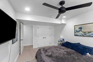 Carpeted bedroom featuring ceiling fan and a closet