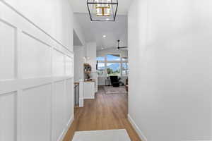 Hall featuring an inviting chandelier, light hardwood / wood-style flooring, and lofted ceiling