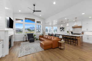 Living room featuring ceiling fan, light hardwood / wood-style flooring, vaulted ceiling, and sink