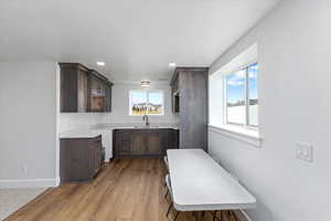 Kitchen with dark brown cabinetry, sink, and light wood-type flooring