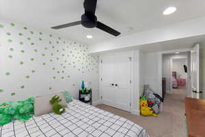 Carpeted bedroom featuring ceiling fan and a closet