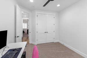 Bedroom with ceiling fan, light colored carpet, and a closet