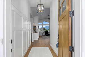 Corridor featuring a notable chandelier, light hardwood / wood-style floors, and lofted ceiling