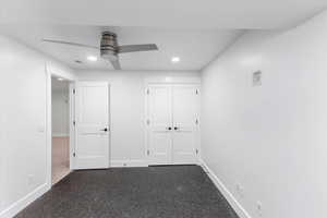 Unfurnished bedroom with ceiling fan, a closet, and dark colored carpet