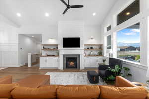 Living room with a tile fireplace, light wood-type flooring, and ceiling fan