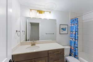 Full bathroom with shower / bathtub combination with curtain, vanity, and toilet