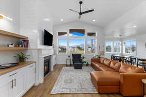 Living room featuring ceiling fan, light hardwood / wood-style flooring, and lofted ceiling