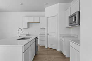 Kitchen featuring stainless steel appliances, sink, a center island with sink, dark hardwood / wood-style floors, and white cabinetry