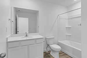 Full bathroom with bathing tub / shower combination, hardwood / wood-style floors, vanity, and toilet