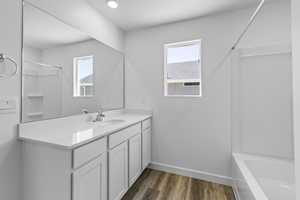 Bathroom with hardwood / wood-style floors, vanity, and shower / bathtub combination