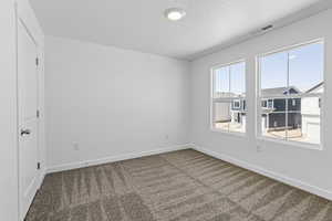 Empty room featuring carpet and a textured ceiling