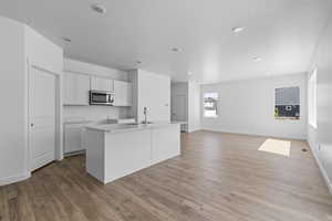 Kitchen featuring light hardwood / wood-style floors, white cabinetry, and an island with sink