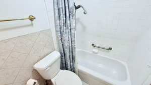 Bathroom featuring toilet, tile walls, and shower / bath combo with shower curtain