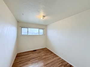 Empty room with a textured ceiling and light wood-type flooring