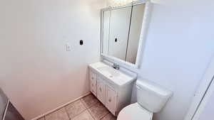 Bathroom featuring toilet, tile patterned flooring, and vanity