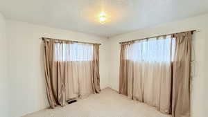 Carpeted spare room featuring a textured ceiling