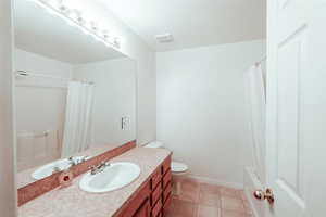 Full bathroom with toilet, shower / bath combo, tile patterned floors, and vanity