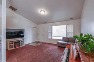 Carpeted living room with lofted ceiling