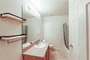 Full bathroom featuring toilet, shower / tub combo, tile patterned flooring, and vanity