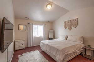 Bedroom with dark carpet and vaulted ceiling