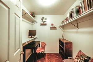 Office space featuring dark carpet and a textured ceiling