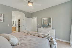 Carpeted bedroom featuring ceiling fan, connected bathroom, and a closet