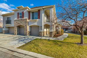 View of front of property featuring a balcony, a front lawn, and a garage