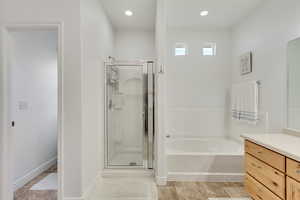 Bathroom with plus walk in shower, vanity, and tile patterned flooring