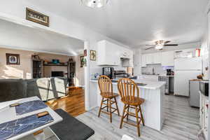 Kitchen featuring stainless steel electric range oven, sink, light hardwood / wood-style flooring, white fridge, and white cabinetry