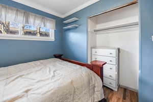 Bedroom with hardwood / wood-style flooring, a closet, and crown molding