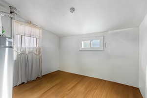 Spare room with wood-type flooring and lofted ceiling