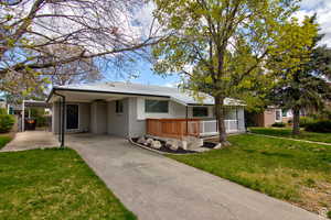 Single story home with a porch, a front yard, and a carport