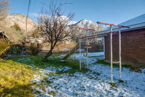 Snowy yard with a playground and a mountain view