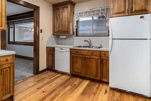 Kitchen featuring decorative backsplash, sink, white appliances, and light hardwood / wood-style flooring