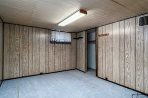 Basement featuring wood walls and light carpet