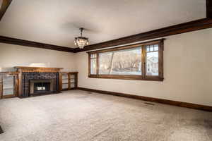 Unfurnished living room with carpet flooring, ornamental molding, and a fireplace