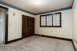 bedroom featuring a textured ceiling, light colored carpet, and a closet