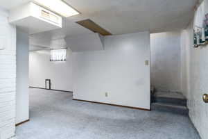 Basement with a textured ceiling and light carpet