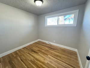 Unfurnished room with wood-type flooring and a textured ceiling