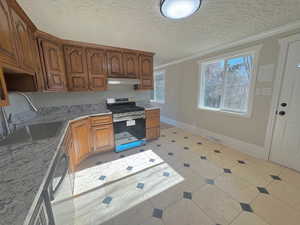 Kitchen with sink, stainless steel appliances, a textured ceiling, and ornamental molding