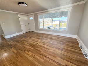 Foyer featuring hardwood / wood-style floors, crown molding, and a textured ceiling