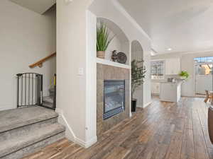 Unfurnished living room with a tiled fireplace, ornamental molding, and hardwood / wood-style flooring