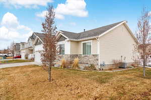 View of side of home with a yard, a garage, and central AC unit