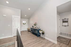 Entrance foyer featuring light hardwood / LVP floors and vaulted ceiling