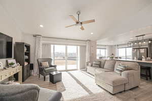 Living room with lofted ceiling, ceiling fan, and LVP flooring