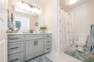 Bathroom featuring tile flooring, vanity, toilet, and a shower with shower curtain