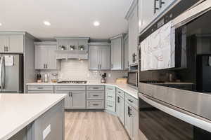 Kitchen featuring gray cabinetry, decorative backsplash, and appliances with stainless steel finishes